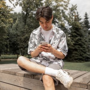Asian man browsing smartphone in park