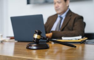 Crop concentrated male judge in formal clothes sitting using modern netbook while working in law office