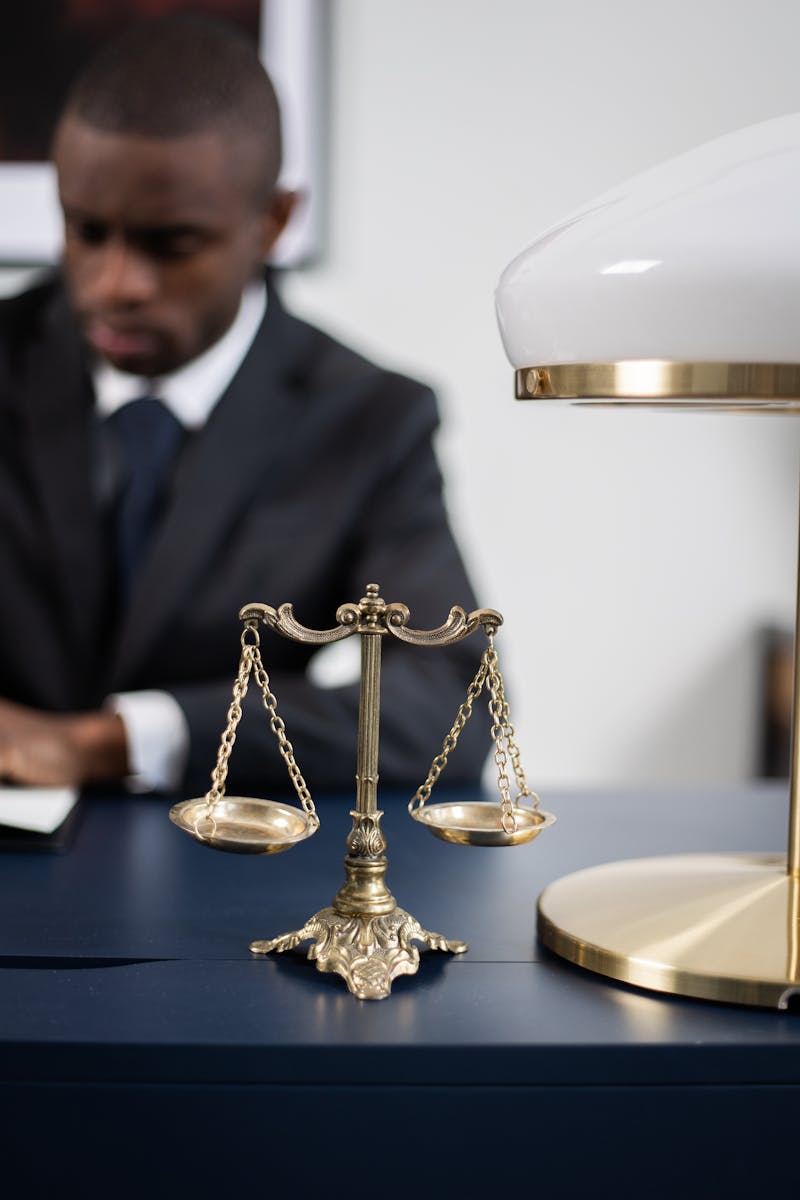 A professional lawyer working at his desk with scales of justice symbolizing fairness and law competence.